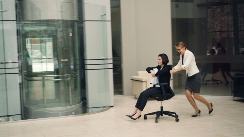 Femmes d'affaires s'amusant en faisant rouler une chaise