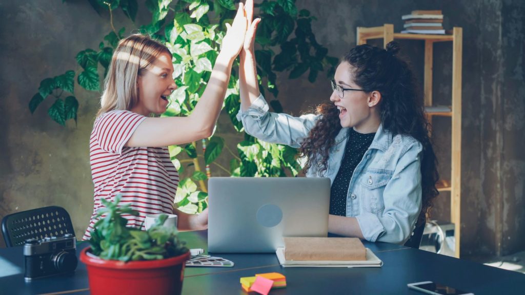 Femmes célébrant en se tapant dans les main devant ordinateur