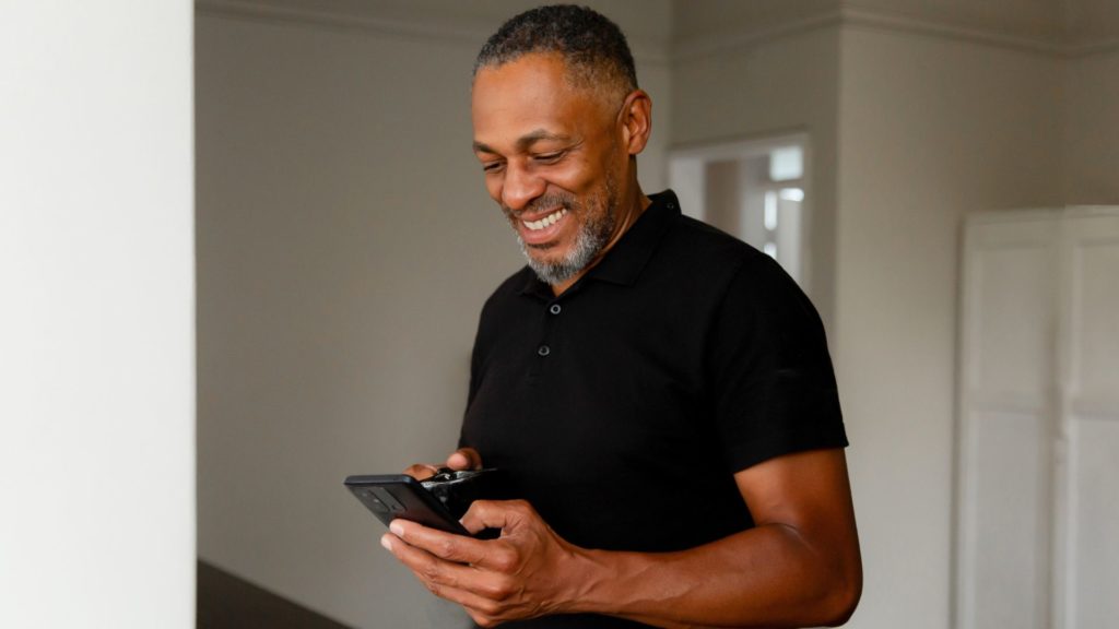 Homme regardant son cellulaire en souriant